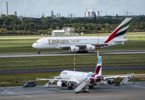Düsseldorf Airport, Eurowings Airbus aircraft on the apron, Emirates Airbus A380-800 taking off, in the background the HKM steelworks in Duisburg, North Rhine-Westphalia, Germany