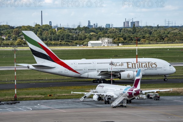 Düsseldorf Airport, Eurowings Airbus aircraft on the apron, Emirates Airbus A380-800 on its way to take-off, in the background the HKM steelworks in Duisburg, North Rhine-Westphalia, Germany