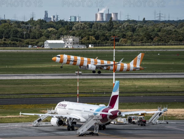 Düsseldorf Airport, Eurowings Airbus aircraft on the apron, Condor Airbus A321-200 taking off, in the background the HKM steelworks in Duisburg, North Rhine-Westphalia, Germany