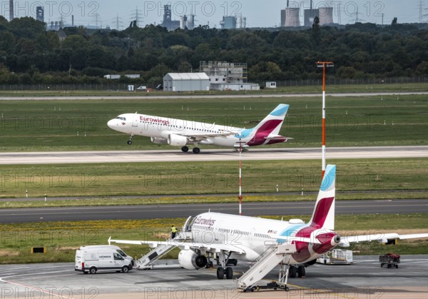 Düsseldorf Airport, Eurowings aircraft taking off, Eurowings Airbus on the apron, skyline of the HKM steelworks in Duisburg, North Rhine-Westphalia, Germany