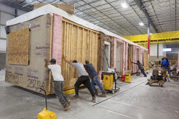 Romulus, Michigan - Workers build apartments in Ginosko Modular 's factory using modular construction methods. They are moving one module to the next assembly station. The units will be assembled into an apartment building in Detroit for low to moderate income households