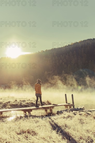 Young woman at Lake Staz near Sankt Moritz in the Engadine in Switzerland. Morning atmosphere with fog in autumn. Reflection of water
