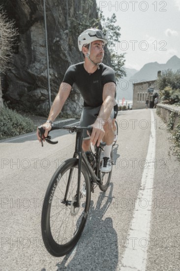 Young man riding a racing bike on Lake Garda. Sunny weather and dolce vita