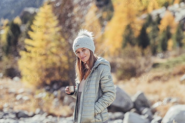 Woman in winter clothes in autumn Engadine with golden trees in Switzerland