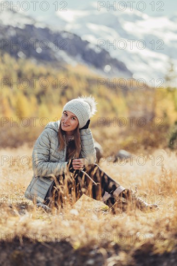 Woman in winter clothes in autumn Engadine with golden trees in Switzerland