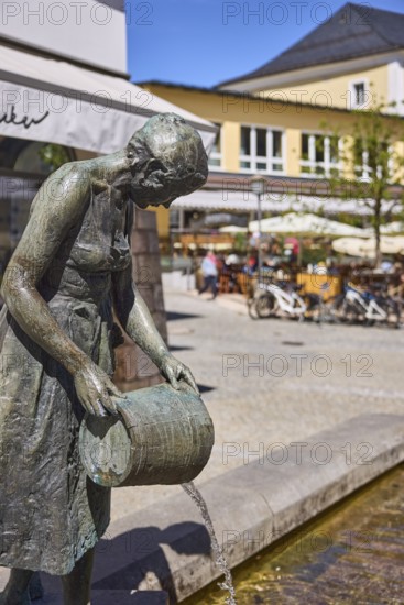 Mother-child fountain, sculptor Fritz Schelle, fountain with bronze sculptures, square, outdoor area of a restaurant with parasols, visitors as secondary motif, general architecture, depth of field, pedestrian zone, blue sky, cloudless, market square, Metzgerstraße, Berchtesgaden, Upper Bavaria, Berchtesgadener Land district, Bavaria, Germany