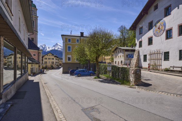General architecture, historical building, sundial, quarry stone wall, parking boxes, vehicles, trees, light-flooded foliage, mountain landscape, mountain, blue sky, cirrostratus clouds, crossing Nonntal with town hall square, Berchtesgaden, Upper Bavaria, district Berchtesgadener Land, Bavaria, Germany