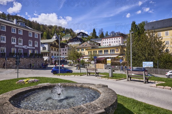 Historic old town, long shot, general architecture, historic buildings, Fischerbrunnen, master stonemason August Wolf, fountain, lawn, flower bed, lantern, mountain landscape, hill, coniferous forest, vehicle, pedestrian as secondary motif, benches, blue sky, cumulus clouds, cirrostratus clouds, Am Fischerbichl, Bahnhofstraße, Berchtesgaden, Upper Bavaria, district of Berchtesgadener Land, Bavaria, Germany