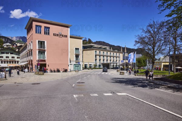 Hotel Edelweiss, buildings, general architecture, trees, road markings lanes, pedestrians as secondary motif, blue sky, cumulus clouds, Weihnachtsschützenplatz, Maximilianstraße, Berchtesgaden, Upper Bavaria, district Berchtesgadener Land, Bavaria, Germany