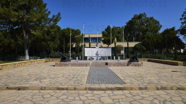 WW2, A memorial with cannons and flags stands on a paved square surrounded by trees, photos referring to