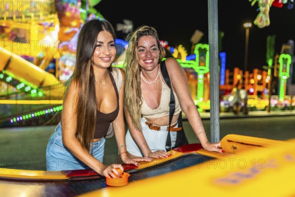 Two friends enjoying a game of air hockey at a brightly lit amusement park, adding excitement to their night out