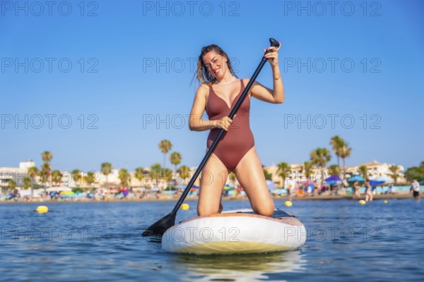 Young woman paddling on a stand up paddle board in the sea near the beach during summer vacation