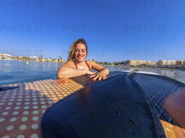 Young woman relaxing on a paddle board, soaking up the sun and enjoying a blissful summer day at the beach by the ocean