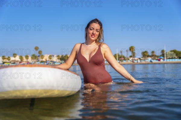 Young woman enjoying paddle surfing in the calm sea on a sunny summer day, embracing the tranquility and watersports lifestyle