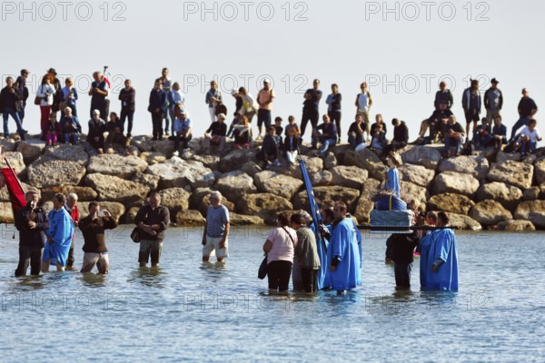 Crowd during pilgrimage, procession by the sea, pilgrims walking through water, statue of the Virgin Mary, Saintes-Maries-de-la-Mer, Camargue, France