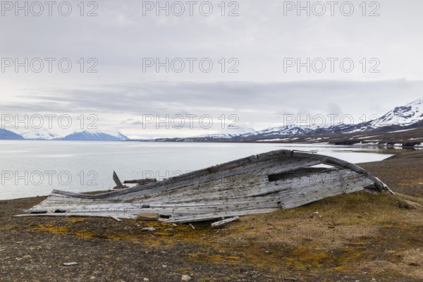 Broken wooden boat on the beach, mountain range, snow, sea, arctic spring, Bamsebu, Spitsbergen, Svalbard