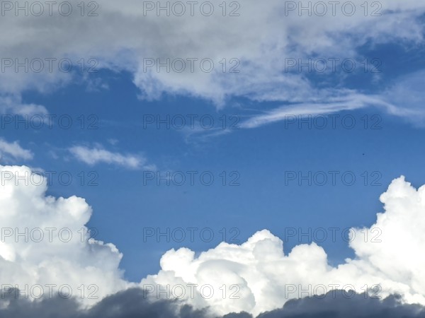 At the bottom of the picture grey white cumulus clouds, at the top altostratus in front of blue sky, International