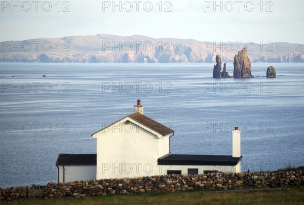 White house overlooking the calm sea and distant cliffs on the horizon, Hillswick, Eshaness, Shetland Islands, Scotland, United Kingdom