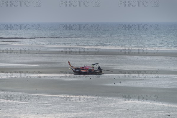 Before sunrise, a lonely longtail boat lies at low tide in the harbour at Sivalai Beach, Koh Mook Island, Satun Province, Southern Thailand, Thailand