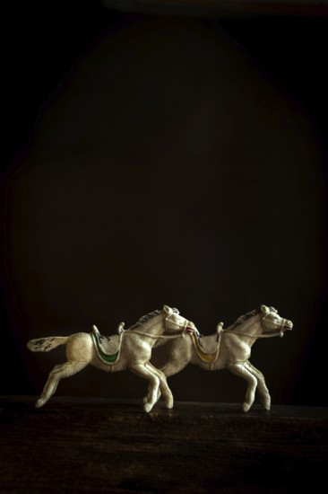 Two intricately designed horse figurines are depicted galloping in sync, creating a sense of movement