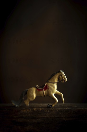 A vintage toy horse appears to be in motion, showcasing intricate details and a nostalgic design. The dark background enhances its classic features and evokes memories of childhood play