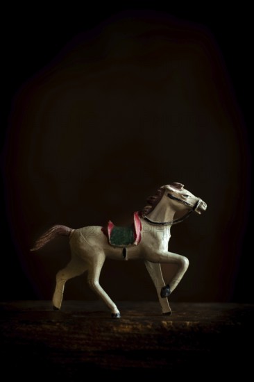 A vintage toy horse trots gracefully across a soft, warm background, highlighting its intricate craftsmanship and evoking a sense of nostalgia and charm