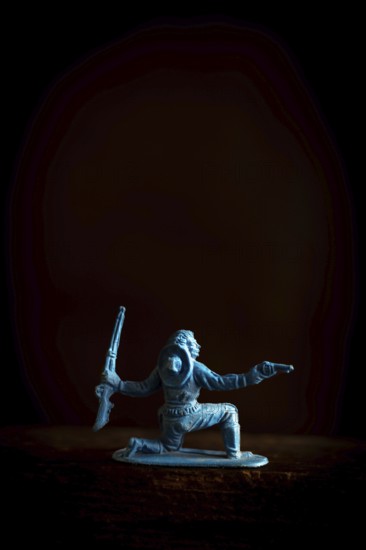 A cowboy figure is captured in a low stance, dynamically poised with two weapons