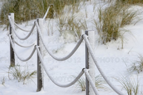 Winter day, onset of winter, demarcation poles with ropes in the snow-covered dune landscape of Norddeich, North Sea, Lower Saxony, Germany
