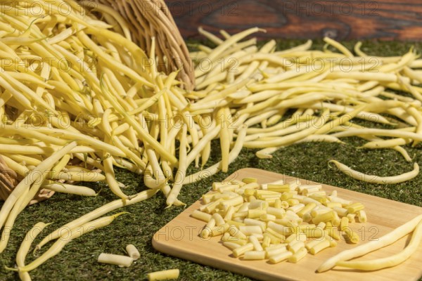 Sliced and whole yellow beans on a board, grass as a base