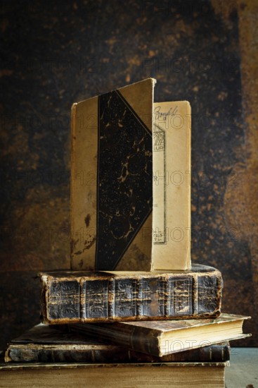 A collection of vintage books is displayed on a wooden table, accompanied by an old-fashioned notebook. The cozy dim lighting enhances the inviting ambiance, perfect for reading or writing