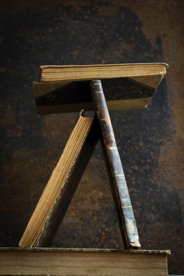 A vintage book stand showcases several old books in a unique position, highlighting their worn textures against a rich, textured background that tells a story