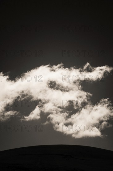 Fluffy clouds float gracefully across a darkening sky, illuminated softly by fading daylight, creating a serene and captivating atmosphere at twilight