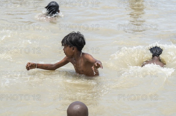 Children bathe in the Brahmaputra River to seek relief from the intense summer heat in Guwahati, India, on June 26, 2025