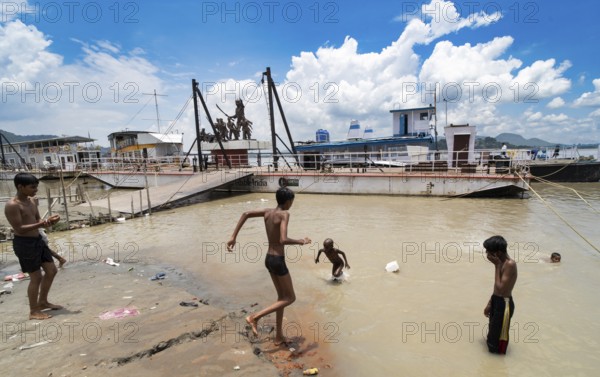 People bathe in the Brahmaputra River to seek relief from the intense summer heat in Guwahati, India, on June 26, 2025