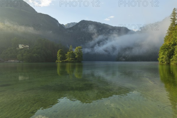 Mystical morning at Königssee in Schönau with boathouses and Christlieger. Sunrise and beautiful wafts of mist over the Königssee in the basin