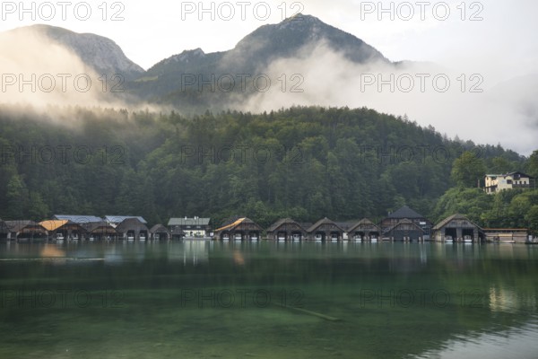 Mystical morning at Königssee in Schönau with boathouses. Sunrise and beautiful wafts of mist over the Königssee in the basin