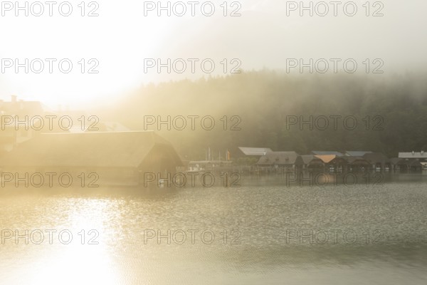 Mystical morning at Königssee in Schönau with boathouses. Sunrise and beautiful wafts of mist over the Königssee in the basin