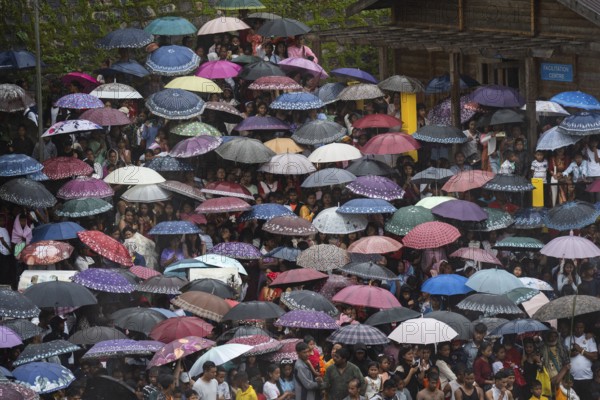 People attend holding umbrellas at an event organised to mark the Behdienkhlam festival in Jowai, India on July 14, 2025. Behdienkhlam is a vibrant annual festival celebrated by the Pnar (Jaintia) community of Meghalaya, especially in Jowai, to drive away plague and diseases and to pray for a good harvest. Observed in July after the sowing season, it features traditional rituals, offerings to ancestral spirits, and the grand procession of beautifully decorated bamboo structures called rots, which are later immersed in a sacred muddy pool known as Ka Aitnar