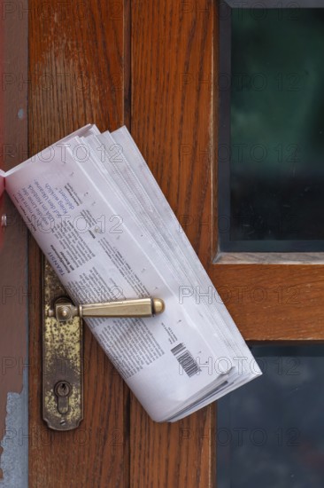 Fresh newspaper waiting at the door in the early morning. Newspaper on the door handle