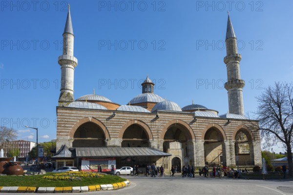 Historic mosque with two minarets on a busy street. The sky is sunny with clear blue. Old Mosque, Eski Camii, Edirne, Eastern Thrace, Turkey