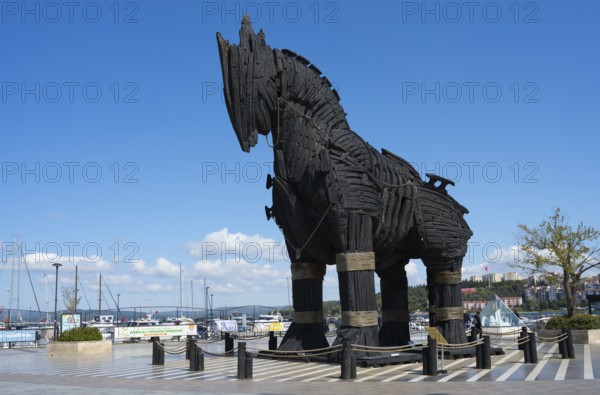 Large black wooden statue of a horse at the harbour with ships and blue sky in the background, Trojan horse, famous film prop, Çanakkale, Canakkale, Marmara region, Turkey