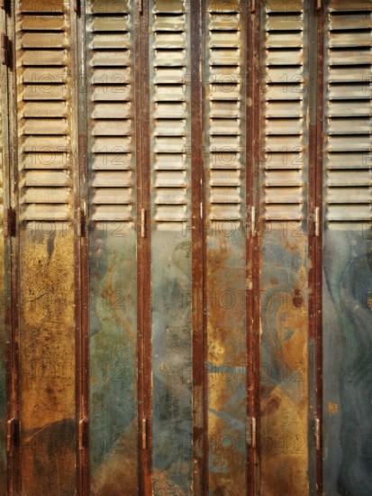 Rustic wooden shutters exhibit a blend of rusty and faded paint, showcasing years of weathering in an urban setting illuminated by natural light, offering a glimpse into its history