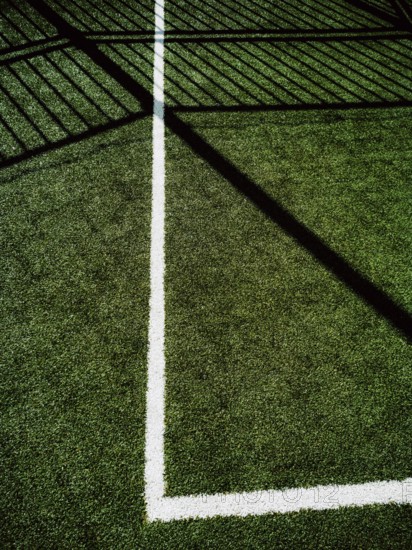 This corner of a sports field features vibrant artificial turf with clear white lines marking the boundary