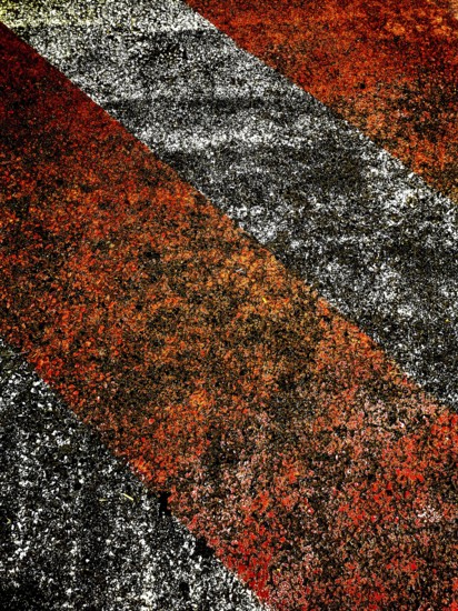 Bold red and black lines create an eye-catching pattern on a rough surface, illuminated by warm late afternoon light, showcasing texture and color contrast effectively