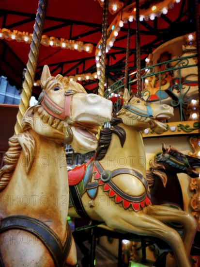 Colorful vintage carousel horses stand at an amusement park, illuminated by soft lights, inviting visitors to enjoy a nostalgic ride in a festive atmosphere