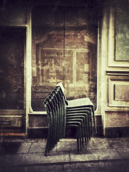 Stacked chairs lean against an inviting building exterior, capturing the peaceful ambiance of a historical street during the early evening. A welcoming eatery hints at nearby dining. France