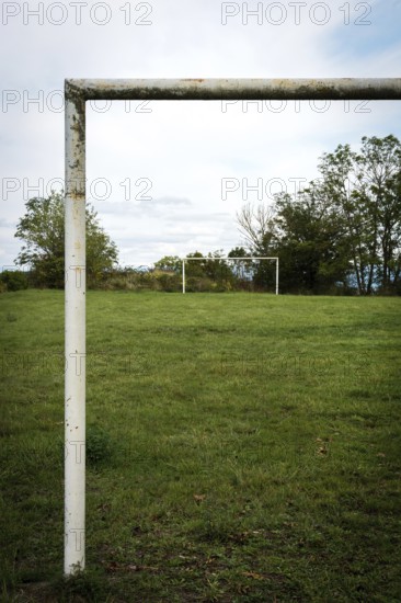Football goalpost in a grassy field under a cloudy sky near a rural area. Auvergne. France