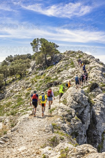 Group of people hiking on a rocky trail high up in the mountains a hot sunny summer day, Mallorca, Spain