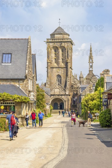 Tourists on city street in the old town of Locronan with the church a sunny summer day, Locronan, Bretagne, France