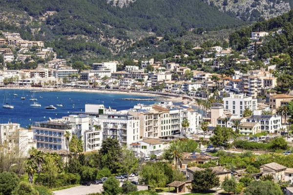 View at a tourist resort by a sea bay by the mountains with houses by the beach a sunny summer day, Port de Sóller, Mallorca, Spain